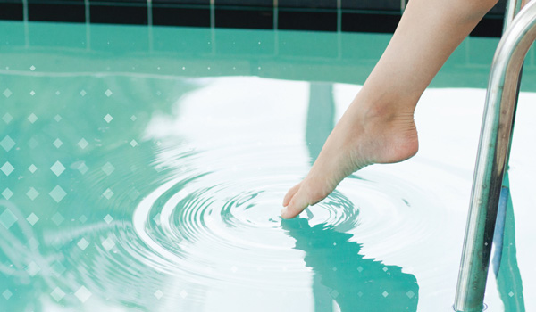 Closeup of a toe dipping into pool water